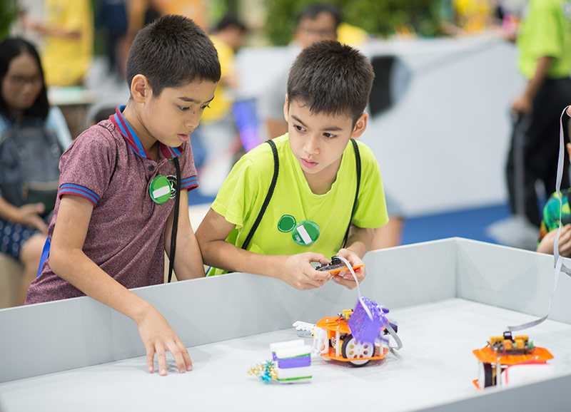 Two children play with stem toys at a trade show.